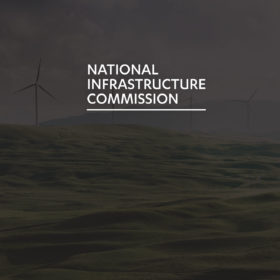 The National Infrastructure Commission logo superimposed on an image of Windmills on a Welsh hillside.